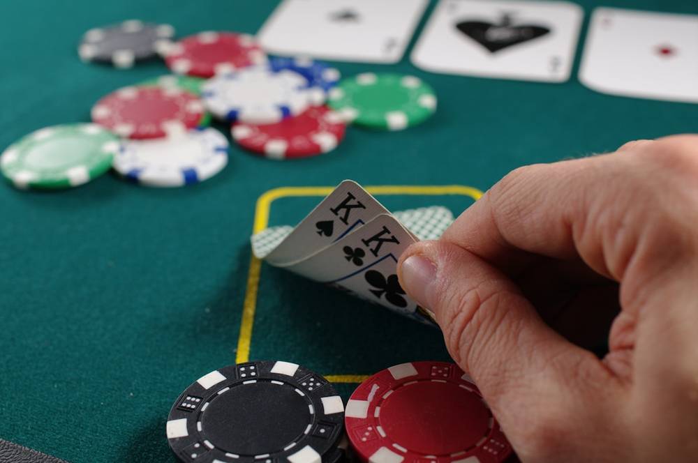Susunan kartu remi dan tumpukan chip poker di atas meja felt hijau